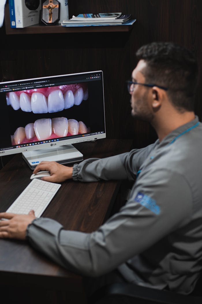 A dental professional closely examines teeth images on a computer monitor in a modern office.