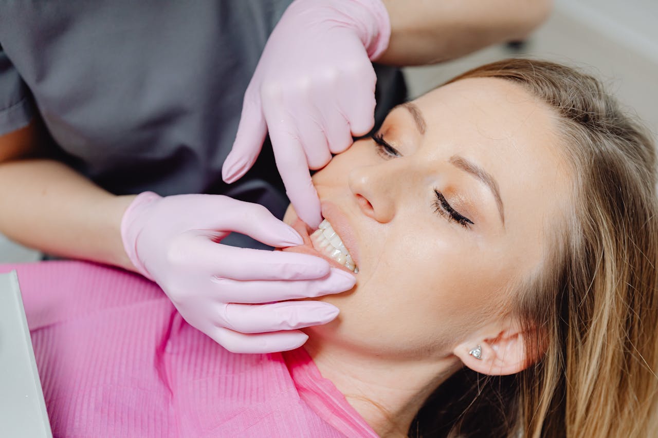 A dentist wearing gloves examines a patients teeth in a close-up view during a dental check-up.